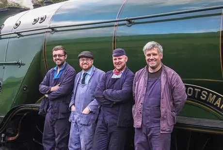 Volunteers next to an engine at East Lancashire Railway